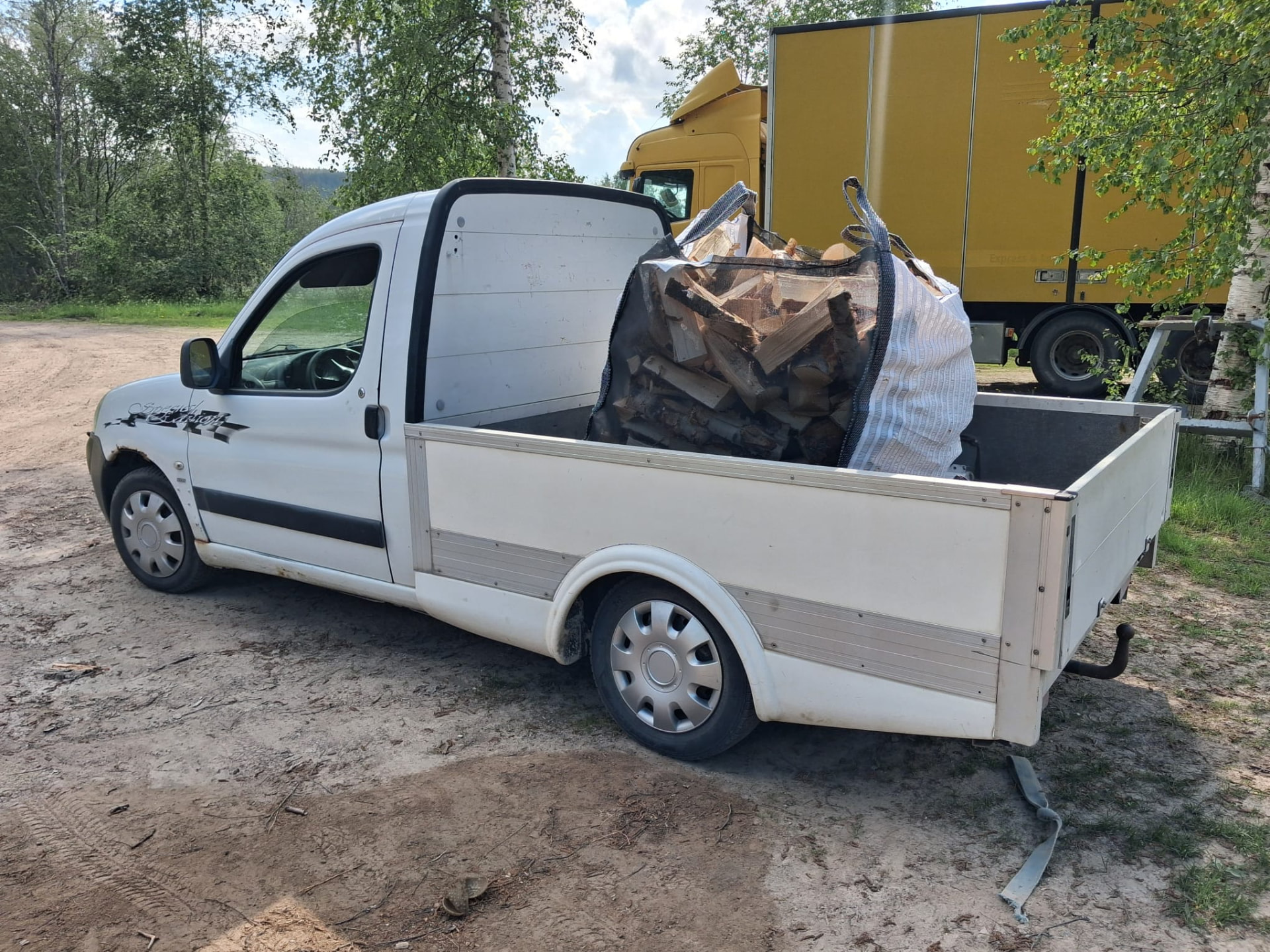 Pickup lastad med en stor säck björkved, redo att levereras
